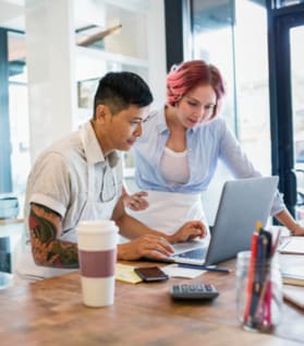 two persons working in laptop