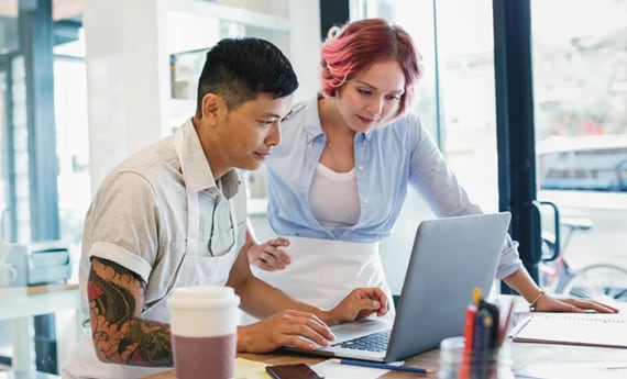 Two people looking at laptop on table